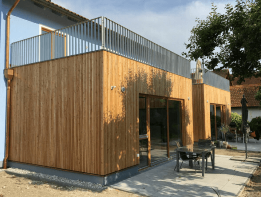 Ein charmantes Haus mit Holzpaneelen und einem einladenden Balkon in einer ruhigen Umgebung.