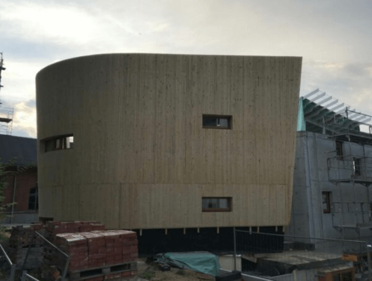 Ein im Bau befindliches Holzgebäude, das die Struktur und Materialien des Bauprozesses zeigt.