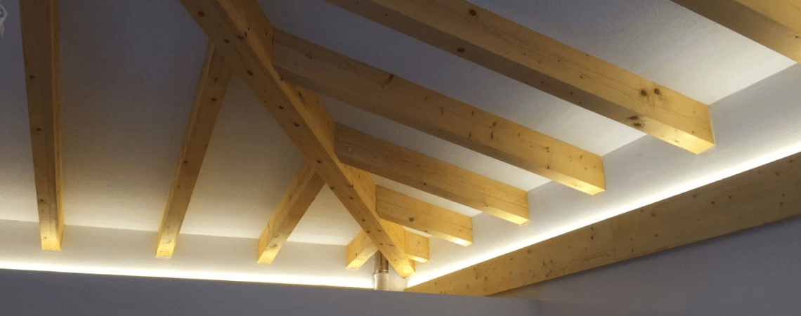 Decke mit Holzträgern und integrierten Lichtern, die eine warme und einladende Atmosphäre schaffen.